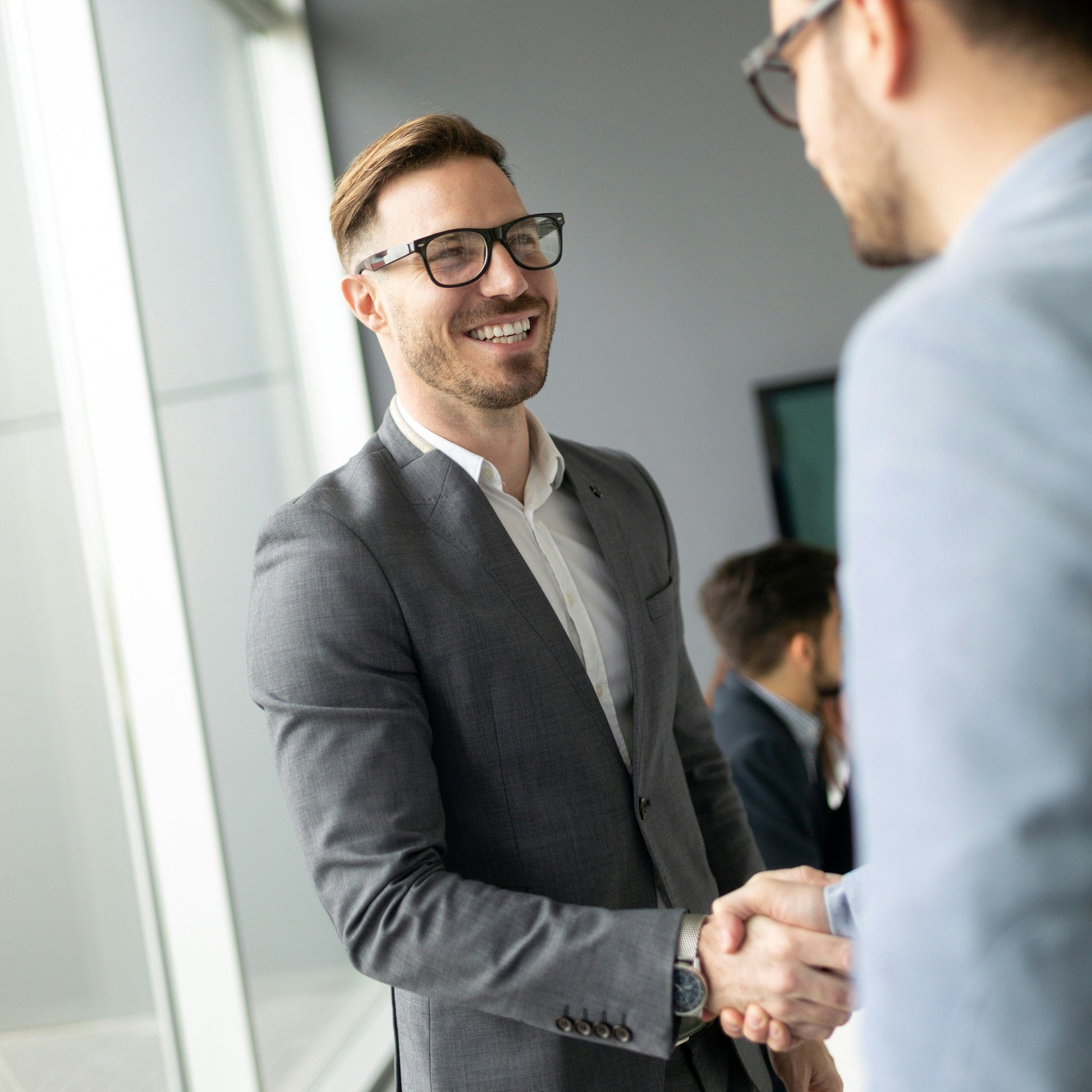 Berater begrüßt Kunden mit Handschlag in modernem Showroom.