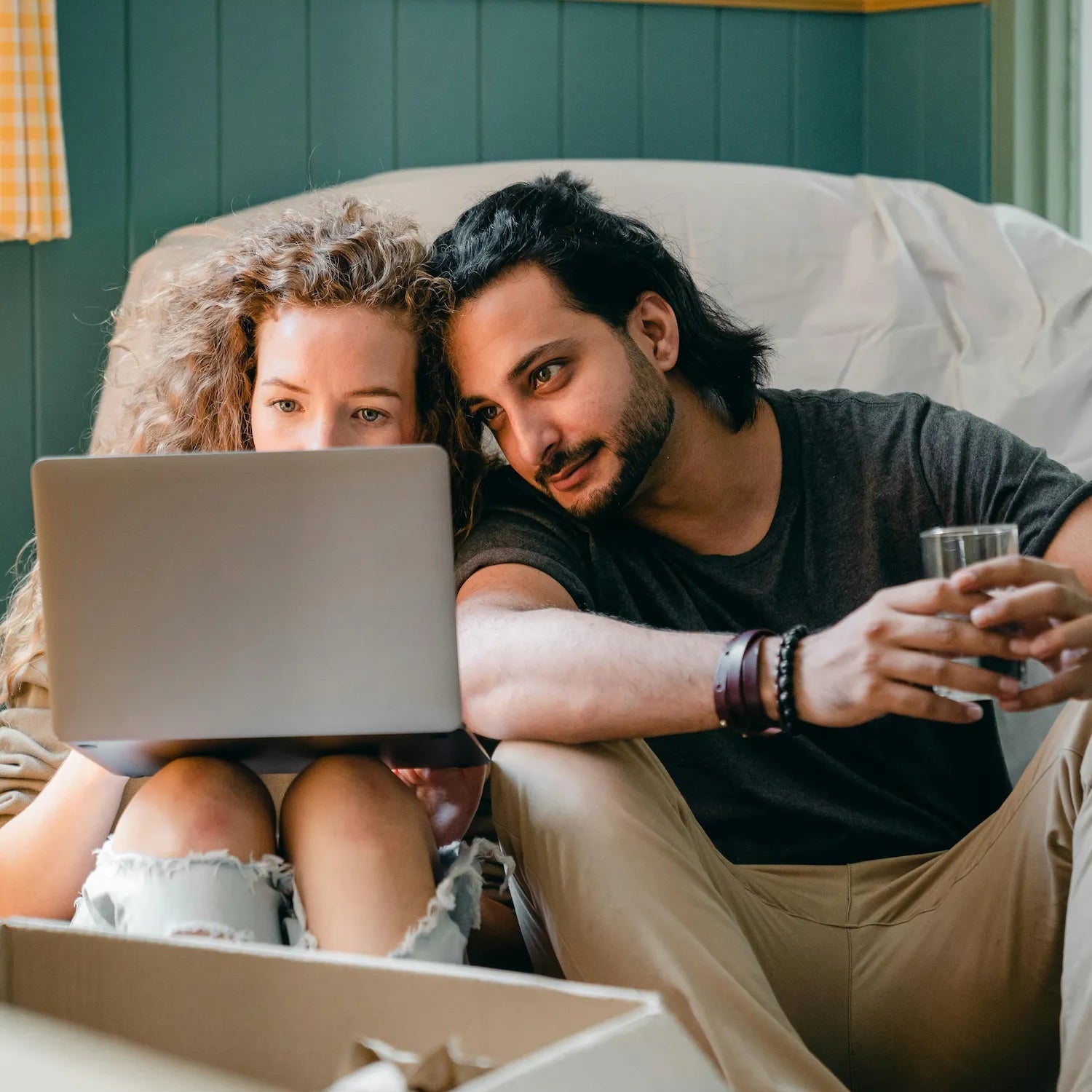 Zwei Personen sitzen gemütlich zusammen und schauen auf einen Laptop, während sie online einkaufen