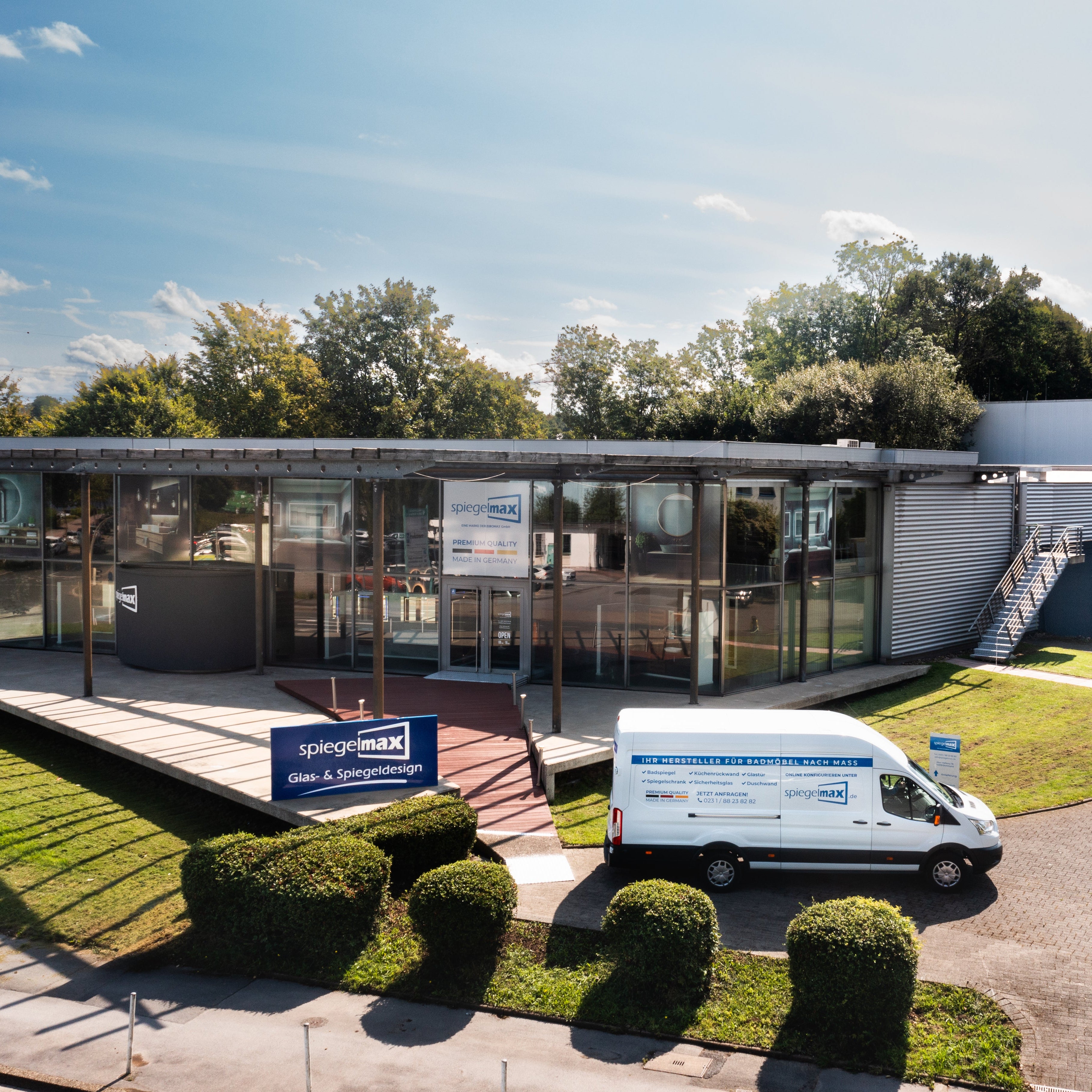 Spiegelmax Firmengebäude mit moderner Glasfassade, Außengelände und Servicefahrzeug im Vordergrund